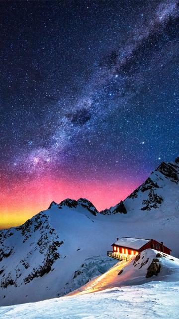 雪山中小木屋旁的极光银河系星星
